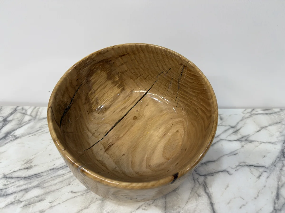Interior view of the rounded wood bowl showing visible grain lines and dark splits.