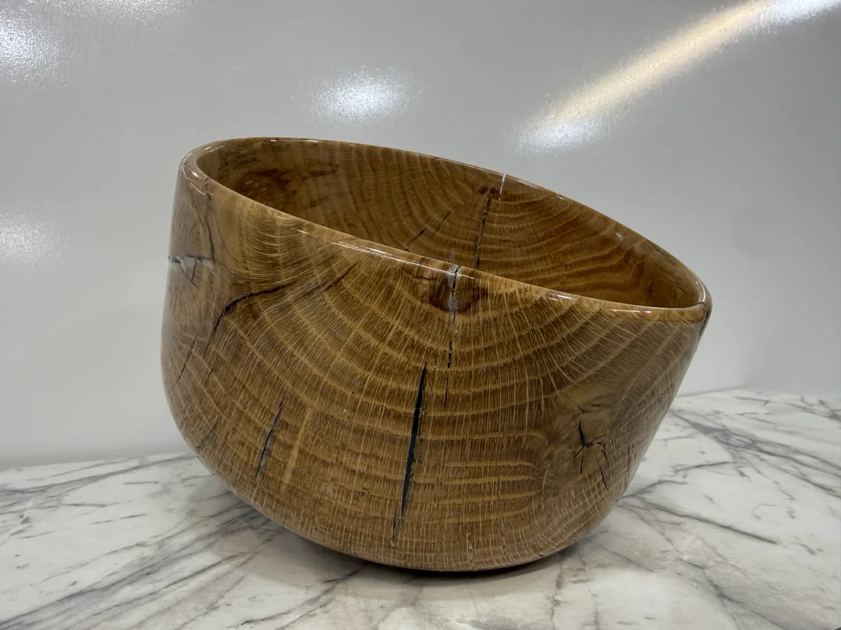 Rounded wood bowl with visible end-grain rings photographed on a light surface.